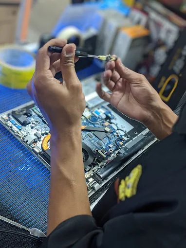 Technician working on a laptop motherboard at Touch Media PJ